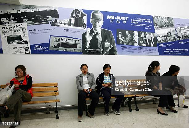 Chinese customers sit on a bench under a picture of Sam Walton, the Founder of Wal-Mart, at Beijing's first Wal-Mart supercenter October 14, 2006 in...
