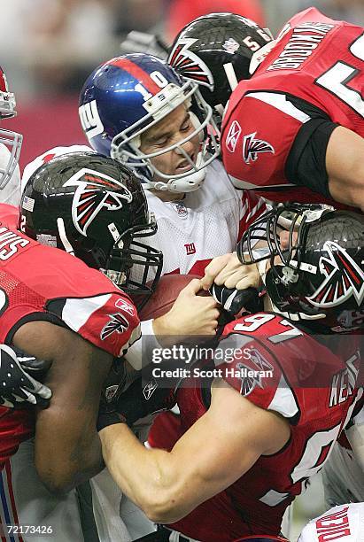 Eli Manning of the New York Giants is sacked by Keith Brooking, Patrick Kerney and Chauncey Davis of the Atlanta Falcons on October 15, 2006 at the...