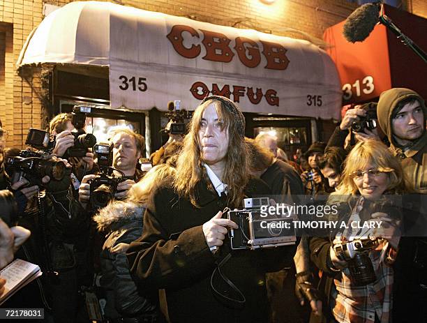 New York, UNITED STATES: Rock star and poet Patti Smith comes outside to take pictures of CBGB, New York's most famous punk bar on its closing night...