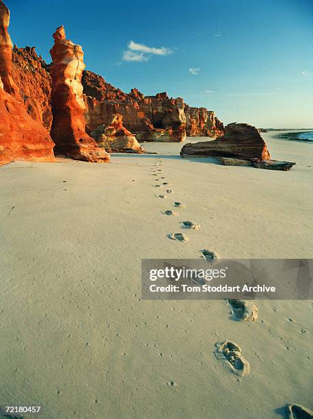 Footprints in the sand and blood red rock formations on the beach at Cape Leveque.