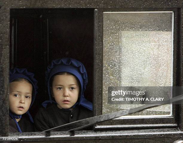 Nickel Mines, UNITED STATES: Amish girls peer out the window of a buggy as they pass through town before the start of a funeral procession of Anna...