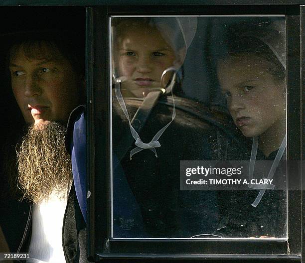 Nickel Mines, UNITED STATES: Amish girls peer out the window of a buggy during the funeral procession of Marian Fisher, age 13, a victim of the Amish...