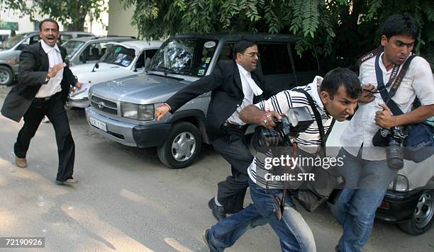 An Indian lawyer assaults press photographers as they cover the murder trial of unseen Santosh Singh at Delhi High Court in New Delhi, 17 October...
