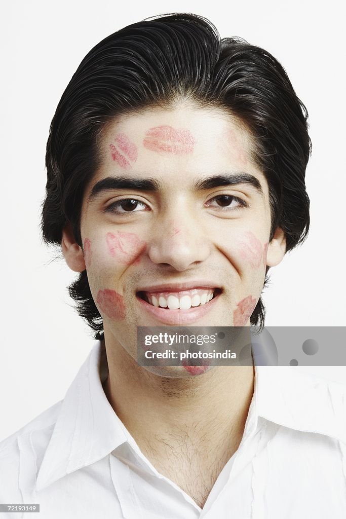 Portrait of a young man covered in lipstick kisses