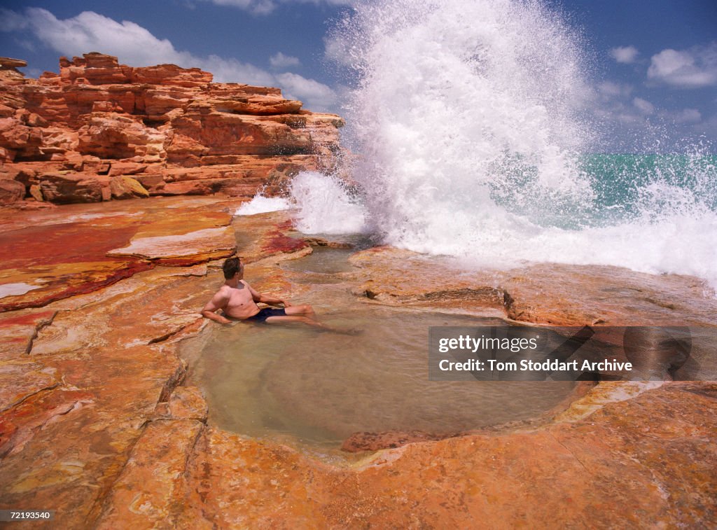 Bathing With Rocks A man bathing in a sea water pool formed by erosion in the rocks at ...