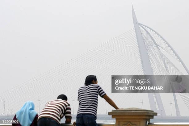 Visitors lean on a ledge while the landmark Seri Wawasan bridge is seen through thick haze in Putrajaya, 18 October 2006. Air quality in Malaysia's...