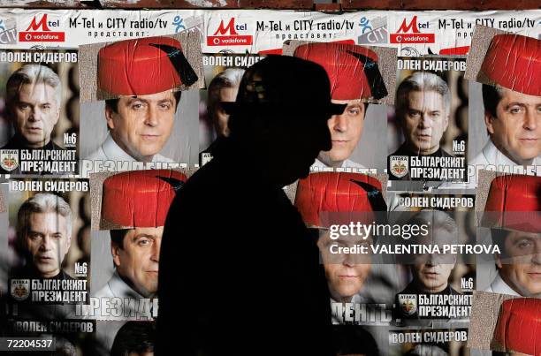 Passer-by looks at disfigured posters of incumbent socialist president Georgy Parvanov "wearing" a Turkish fez, and ultra-nationalist candidate Volen...