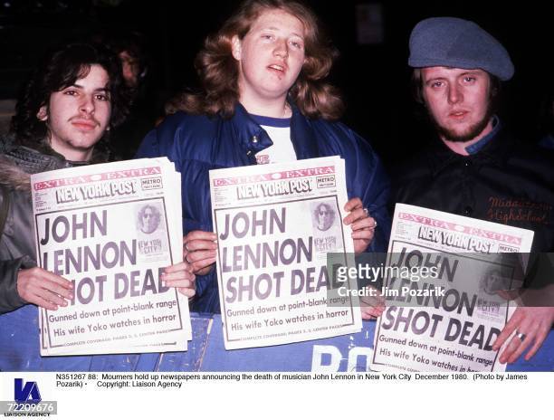 Mourners hold up newspapers announcing the death of musician John Lennon in New York City December 1980. (Photo by James Pozarik/Getty Images