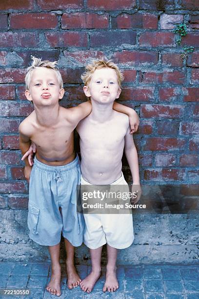 boys standing against wall - geschwister frech stock-fotos und bilder