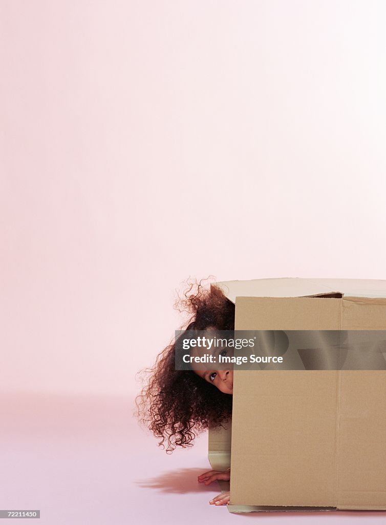 Girl hiding in cardboard box