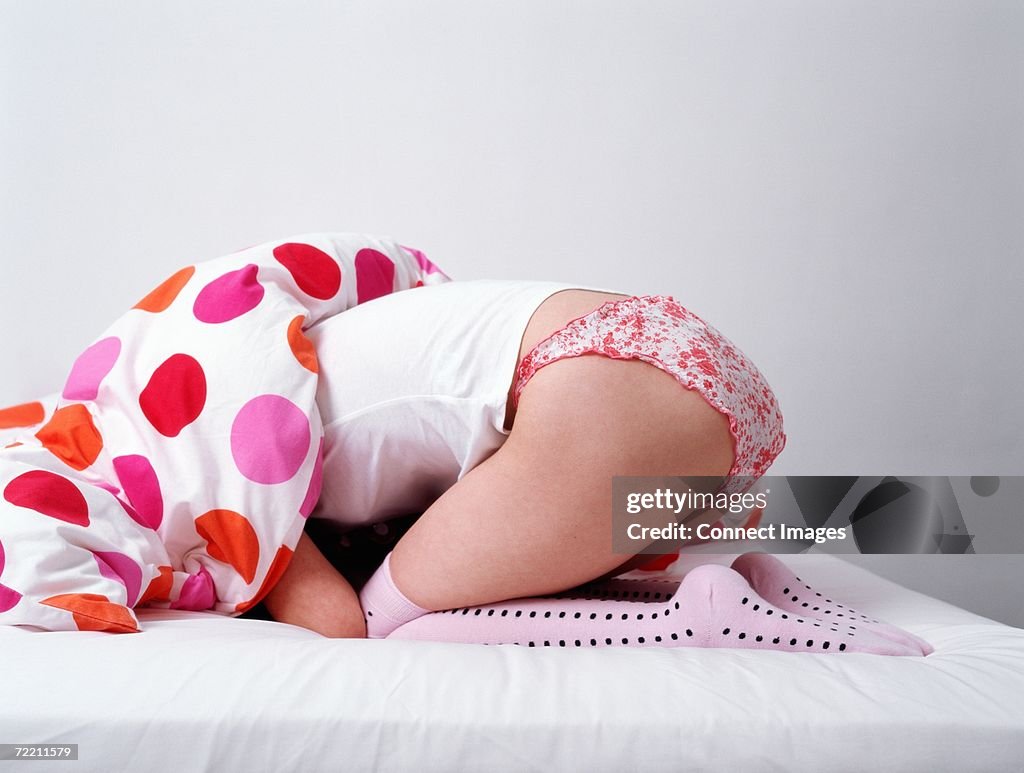 Woman hiding her head under a duvet