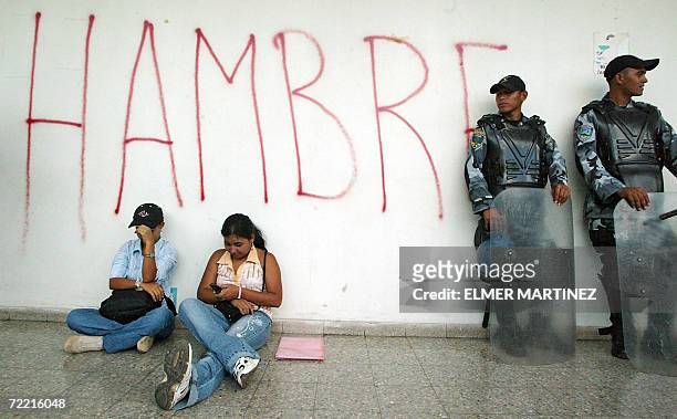 Tegucigalpa, HONDURAS: Dos maestras hondurenas permanecen sentadas junto a policias anti-disturbios durante una protesta en reclamo del pago de...