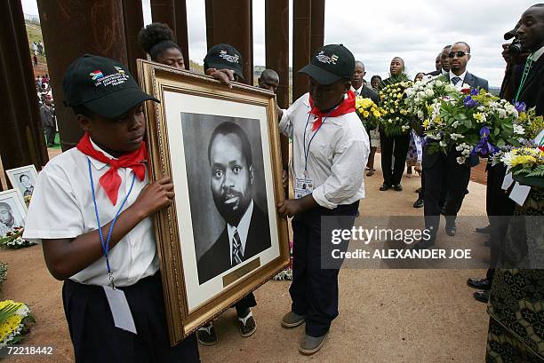 Members of Samora Machel's family hold flowers behind his portrait 19 October 2006 in Mbuzni at a memorial built on a hill where Samora Machel died...