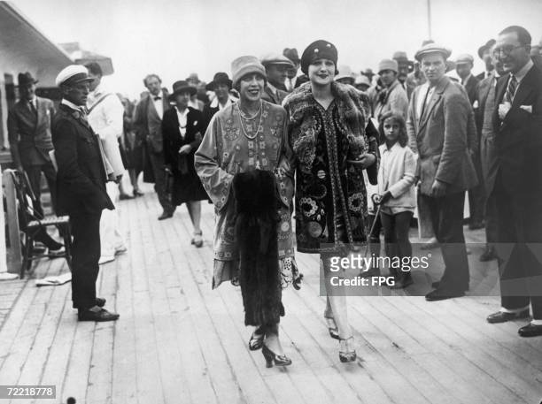 Two young women in embroidered ethnic jackets on the boardwalk at Deauville, in northern France, circa 1925.