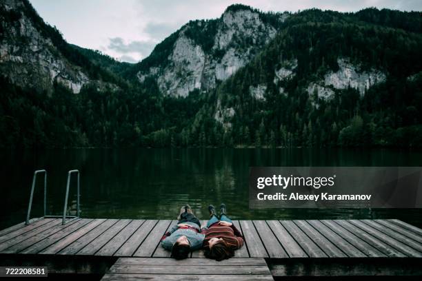 caucasian couple laying on dock near scenic view of mountain - spital am pyhrn stock pictures, royalty-free photos & images