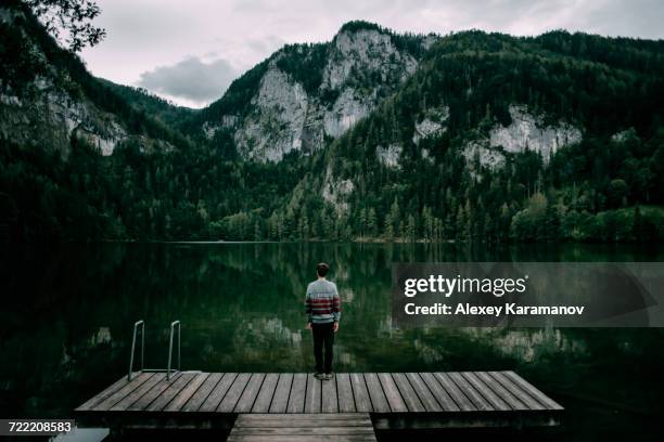 caucasian man standing on dock admiring scenic view of mountain - spital am pyhrn stock pictures, royalty-free photos & images