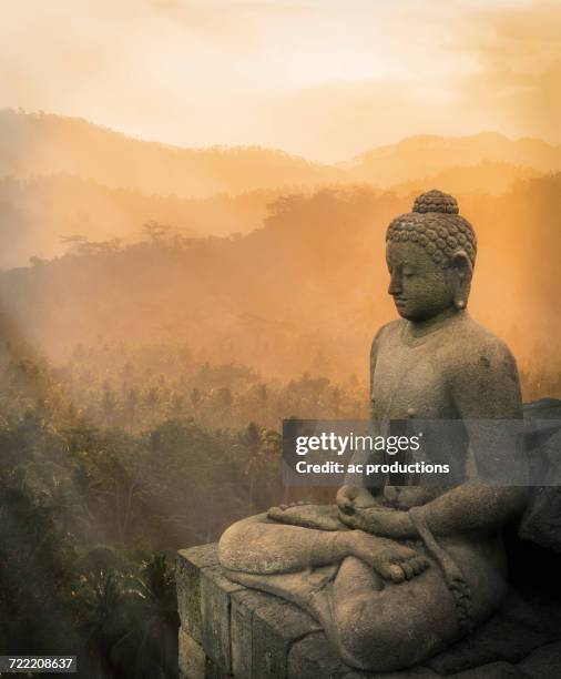 statue of buddha at sunset, borobudur, java, indonesia - boeddha stockfoto's en -beelden