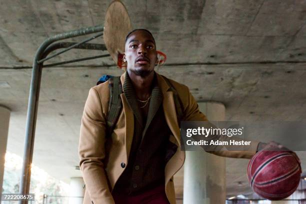 black man wearing backpack playing basketball under overpass - dribbling sport fotografías e imágenes de stock