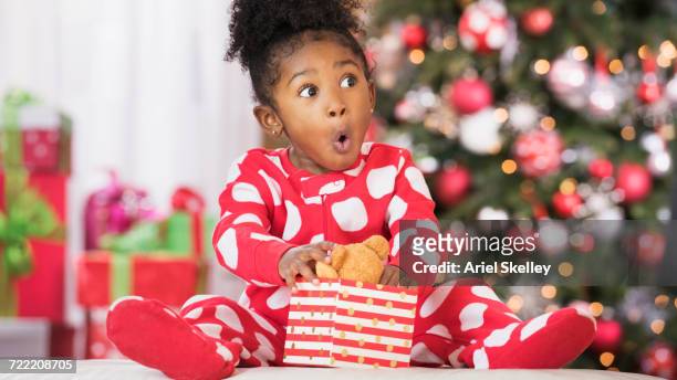 surprised black girl holding teddy bear toy on christmas - christmas presents stock-fotos und bilder