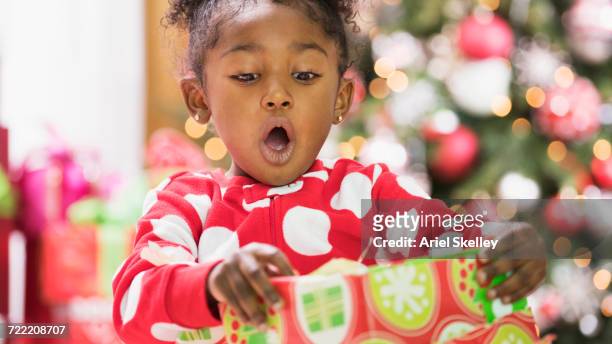 Surprised Black girl opening gift box on Christmas