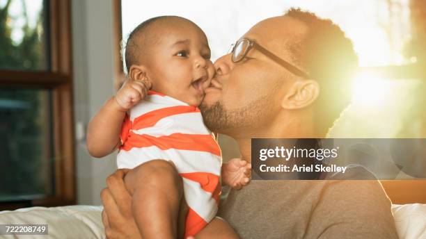 black father kissing baby son on cheek - famille avec des lunettes de vue photos et images de collection