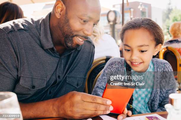 father and daughter sitting at restaurant table texting on cell phone - child foodie photos et images de collection