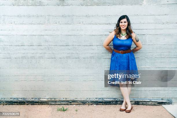 portrait of smiling mixed race woman leaning on wall - blue dress imagens e fotografias de stock