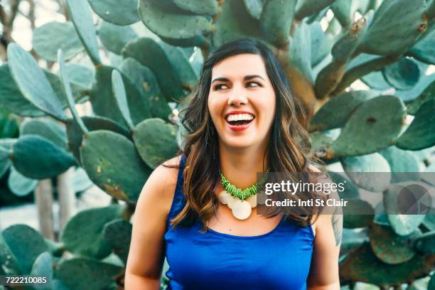 smiling mixed race woman near cactus - collar up stockfoto's en -beelden