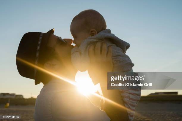 sun beaming between caucasian father and baby son - baby father hug side stock pictures, royalty-free photos & images