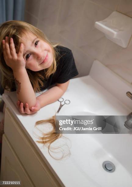 caucasian girl cutting her hair in bathroom - scissor stock-fotos und bilder