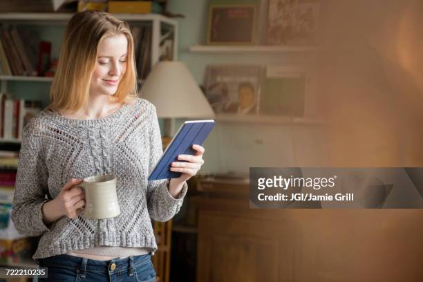 smiling woman drinking coffee and using digital tablet - e reader stock-fotos und bilder