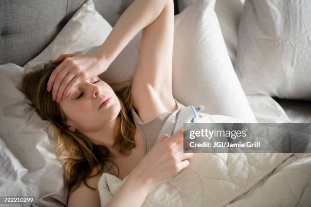 woman laying in bed with headache - koorts stockfoto's en -beelden