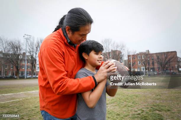 native american father teaching son to throw football - aboriginal family stock-fotos und bilder