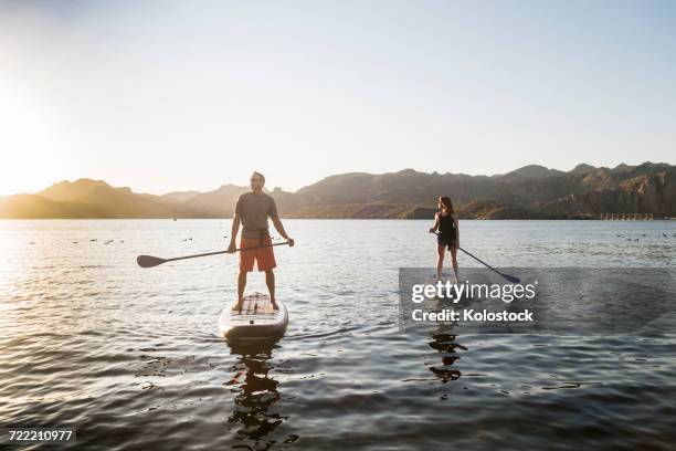 couple standing on paddleboards in rover - paddle surf foto e immagini stock