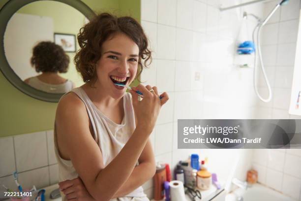 woman brushing teeth in bathroom - brushing teeth ストックフォトと画像