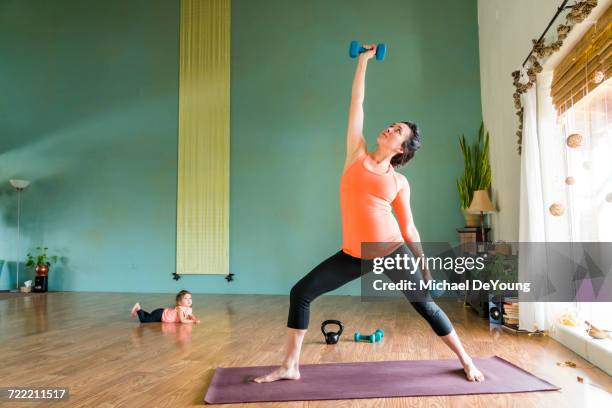 Daughter watching Mixed Race expectant mother lifting weights