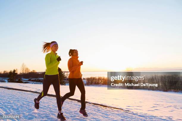 women running on snow in winter - freeze motion stock-fotos und bilder