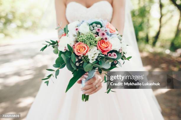 caucasian bride holding bouquet of flowers outdoors - europe bride stock-fotos und bilder