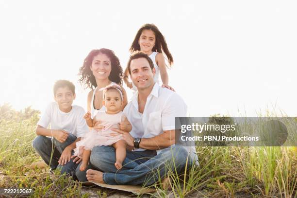 portrait of mixed race family sitting in grass - perfection imagens e fotografias de stock