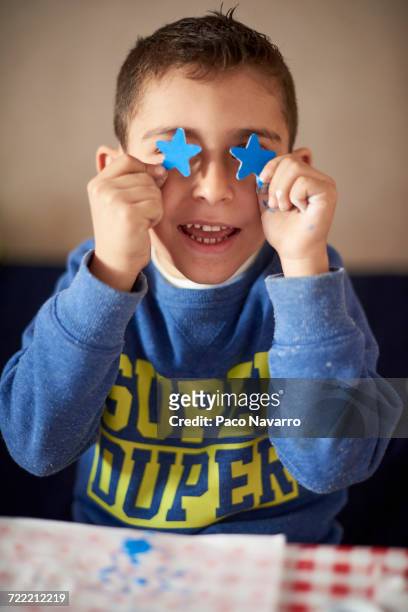 hispanic boy covering eyes with blue stars at table - zapopan stock pictures, royalty-free photos & images