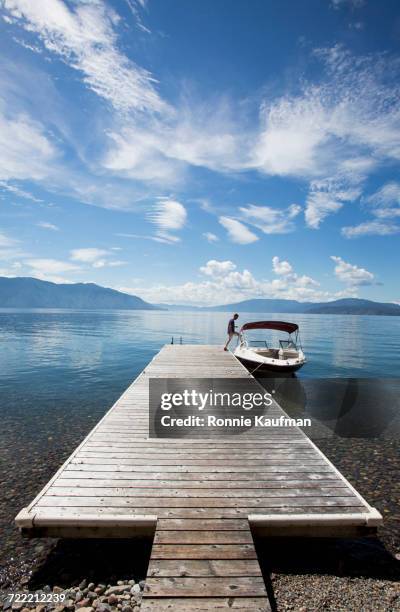 caucasian man boarding boat in river from wooden dock - embarcar fotografías e imágenes de stock