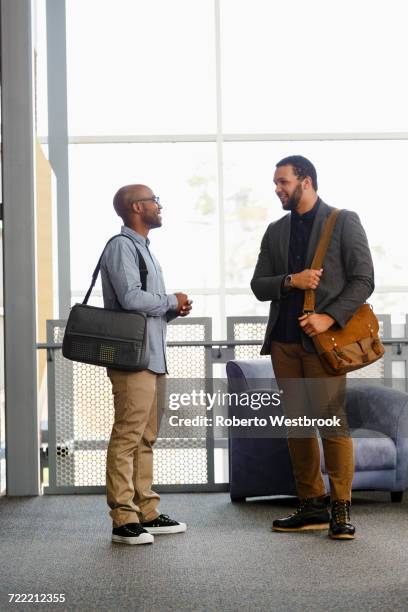 men carrying briefcases talking in lobby - borsa messenger foto e immagini stock