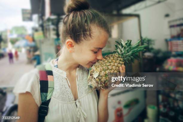 caucasian woman smelling pineapple at market - vietnamese food stockfoto's en -beelden