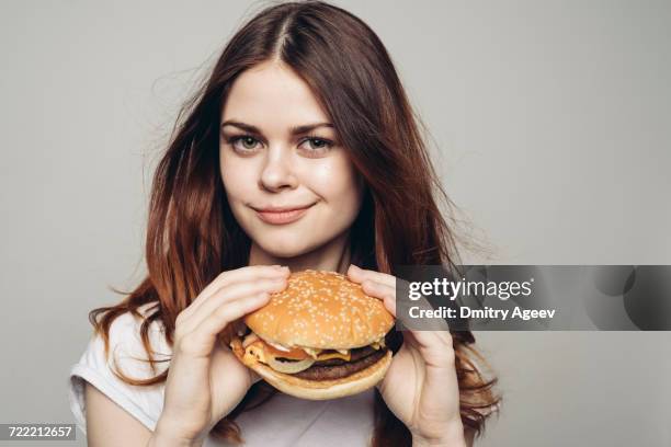 grinning caucasian woman holding cheeseburger - burger portrait photos et images de collection