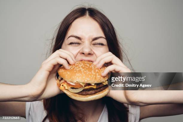 caucasian woman eating cheeseburger - biting on something stock-fotos und bilder