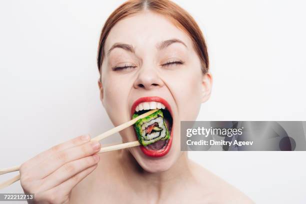 caucasian woman eating sushi with chopsticks - woman mouth stock pictures, royalty-free photos & images