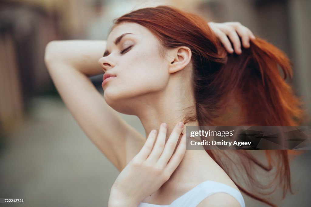 Caucasian woman holding hair and rubbing neck