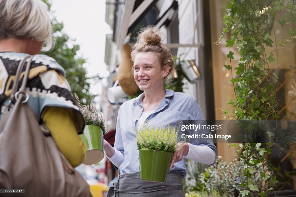 Florist showing plants to female shopper at storefront