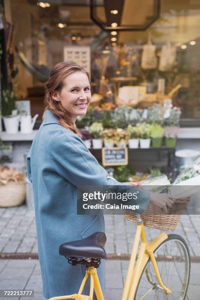 portrait smiling woman walking bicycle at urban storefront - shopping with bike stock-fotos und bilder