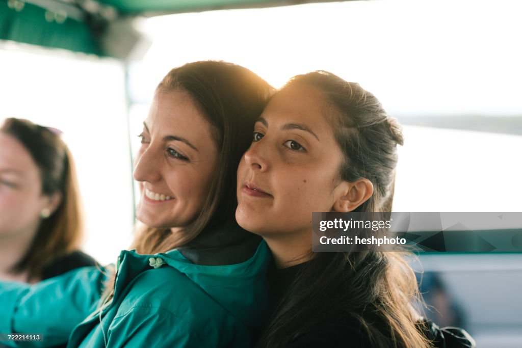 Three adult sisters looking out from boat on coast of Maine, USA